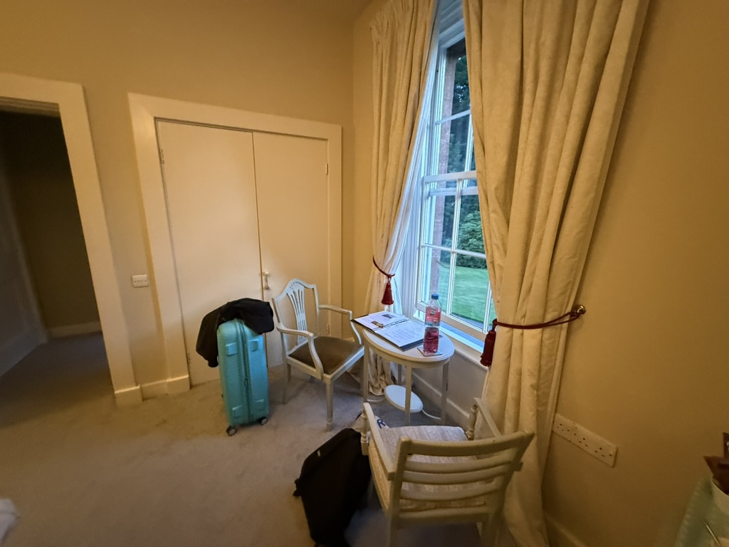 Small table by window with two chairs, suitcase, and bags in a cozy room.