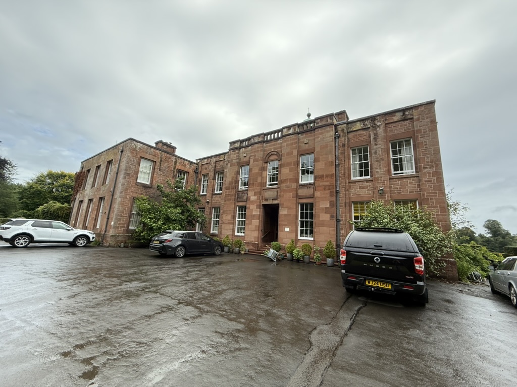 Warrick Hall, a large historic stone building with parked cars in front.