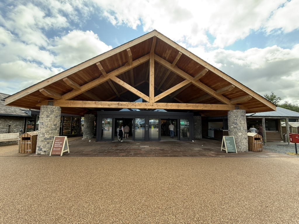 Entrance of Tebay Services with timber roof, stone pillars, and people entering.