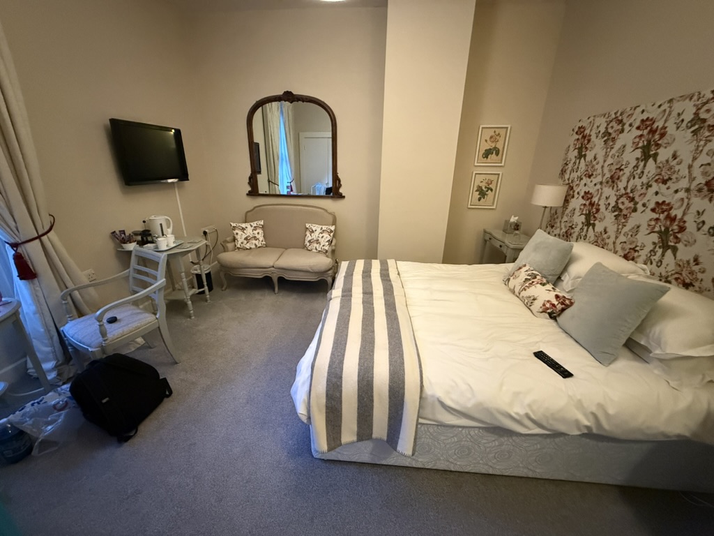 Cozy bedroom with floral headboard, loveseat, and tea set on a small table.