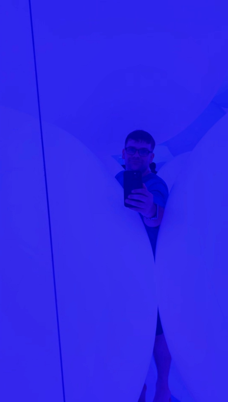 Selfie in blue lighting from behind two giant orbs